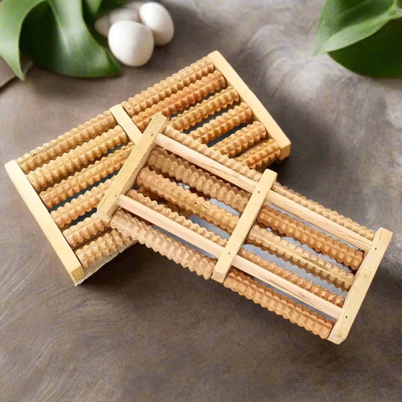 Wooden foot roller on a gray surface with green leaves in the background